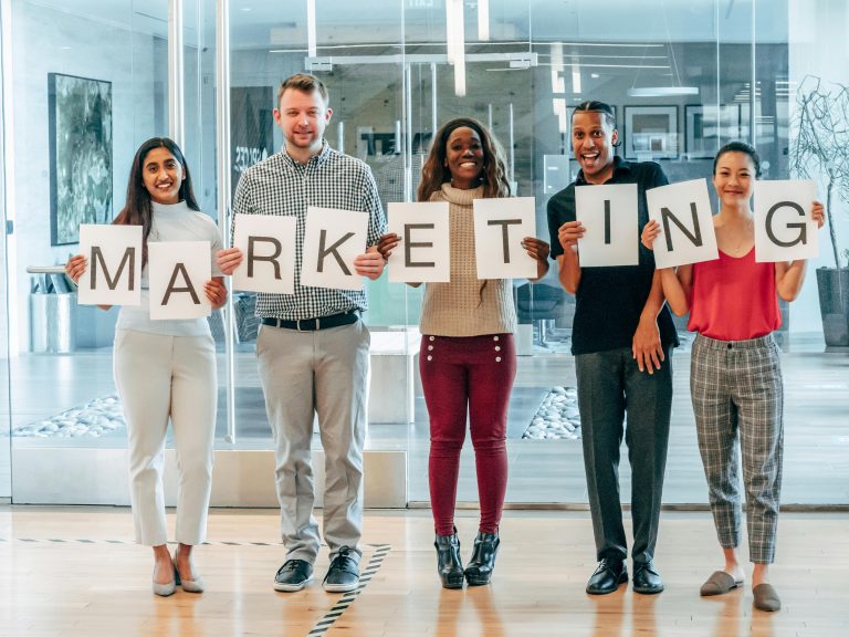A group of people holding letter signs that spell out Marketing.