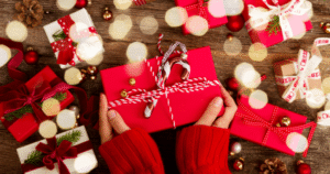 person holding a gift wrapped in red paper with a candy cane ornament